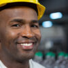 Close up portrait of smiling male worker wearing hard hat in warehouse